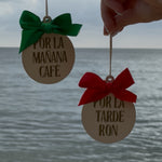 Two round wooden ornaments with green and red bows against a beach background