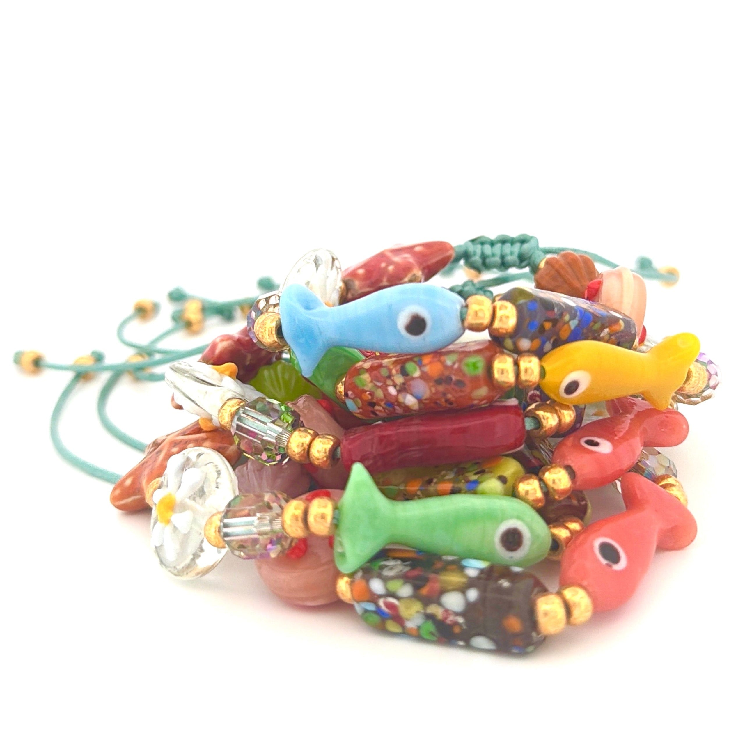 Colorful beaded bracelets with fish charms on a white background