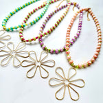 Two necklaces with colorful beads and two gold flower-shaped pendants on a white background.