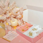 Gift box with PERSONALIZED Jewelry on a pink surface with decorative lights